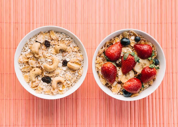 Two bowls with oatmeal and corn flakes on table