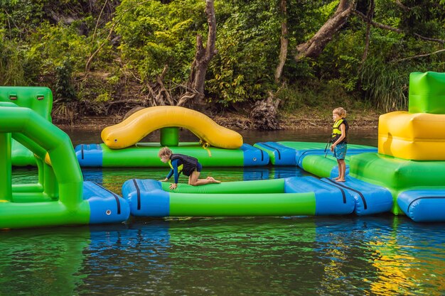 Two boy runs an inflatable obstacle course In the lake