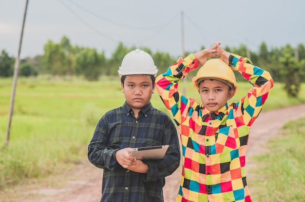 Two boy wearing helmet engineer holding tablet standing outdoor