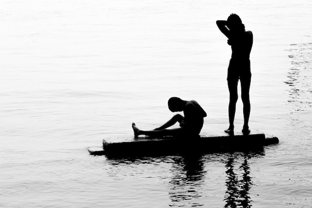두 소년이 강물에서 목욕을 하며 즐거운 시간을 보내고 있습니다. 햇빛에 대한 이미지 실루엣 이미지