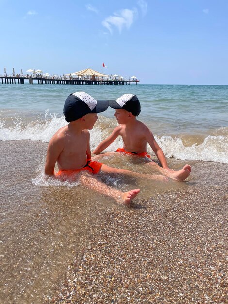 Photo two boys are sitting on the beach