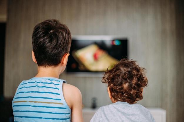 2人の男の子がテレビで興味深いテレビ番組を見ています 子供の家 休憩所の活動