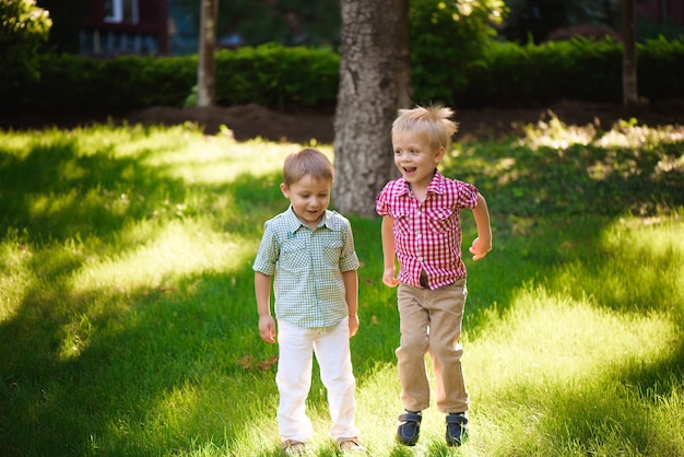 Two boys brothers playing and jumping outdoors in a park.