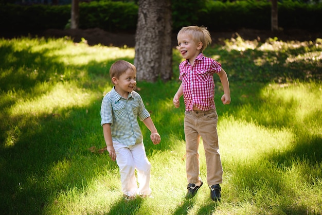 Two boys brothers playing and jumping outdoors in a park.