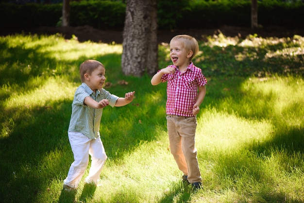 Two boys brothers playing and jumping outdoors in a park.