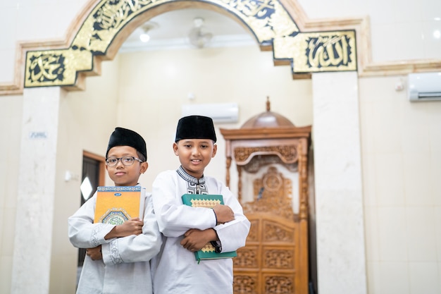 Photo two boys holding holy quran