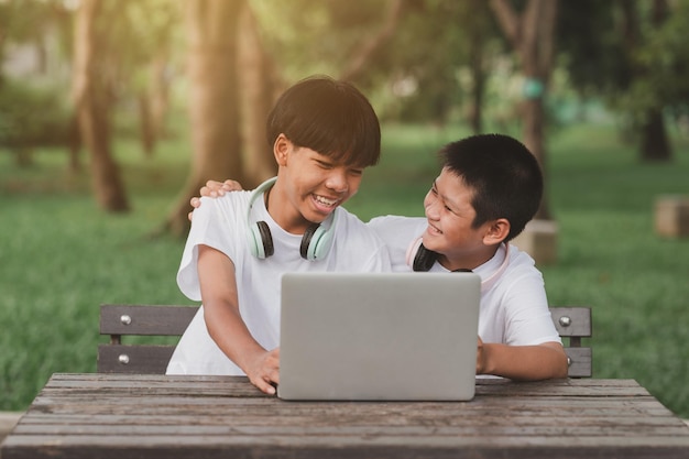 Two boys sit in their garden. Children happily play computer games.