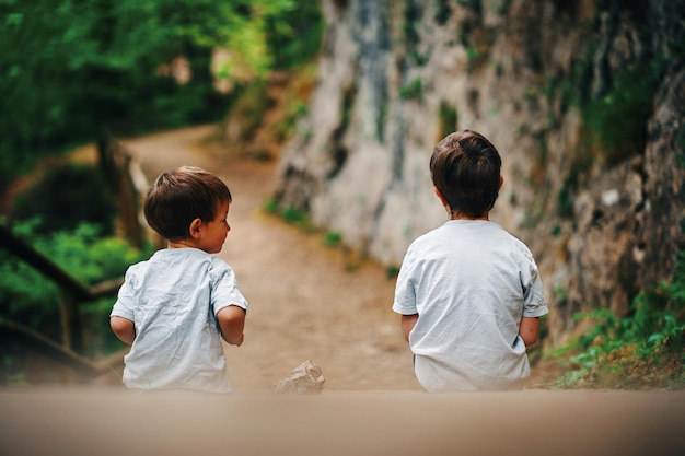 Two boys on a trail looking at a rock wall