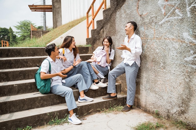 Foto due ragazzi e due ragazze delle scuole superiori in uniforme si sono riuniti con i loro amici sulle scale