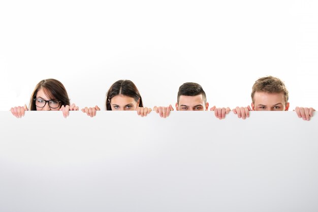 Two boys and two girls peeking behind a sign