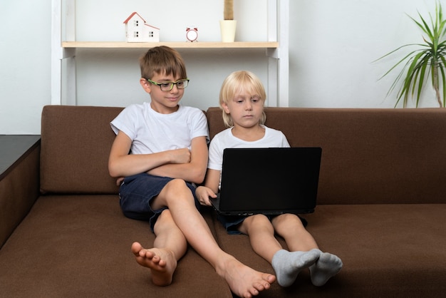 Фото Два мальчика смотрят обучающее видео на ноутбуке. дети с ноутбуками в руках. домашнее обучение