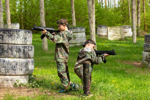 Two boys weared in camouflage playing laser tag in special forest playground