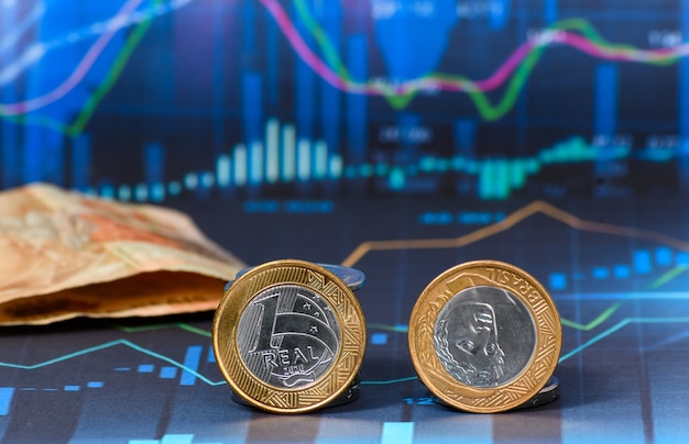 TWO BRAZILIAN MONEY COINS ON A FINANCIAL MARKET GRAPHIC