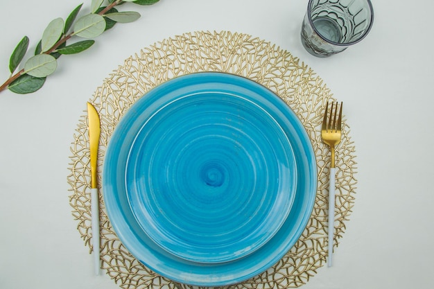 Две ярко-голубые тарелки с спиральным рисунком разных размеров стоят одна на одной на золотом