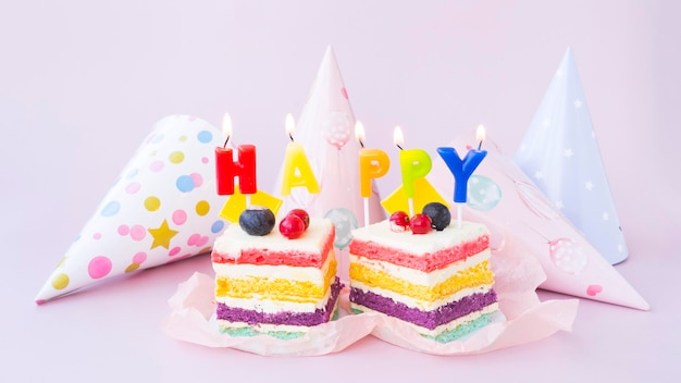 사진 해피라는 단어 모양의 두 개의 밝은 무지개 케이크와 촛불