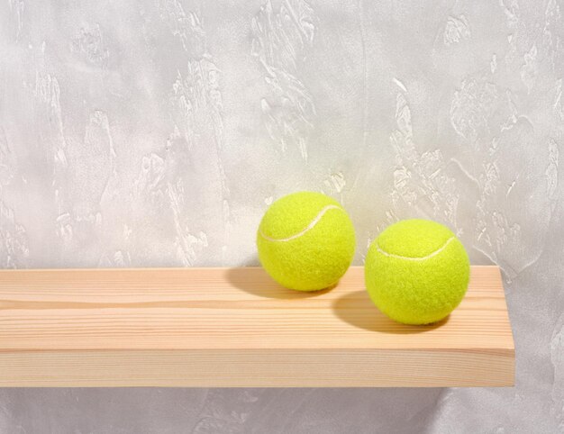 Two bright yellow tennis balls on a gray concrete background Copy space for text Sport and energy