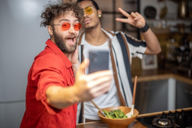 屋内で電話で自分撮りをしている2人の明るい服を着たスタイリッシュな男