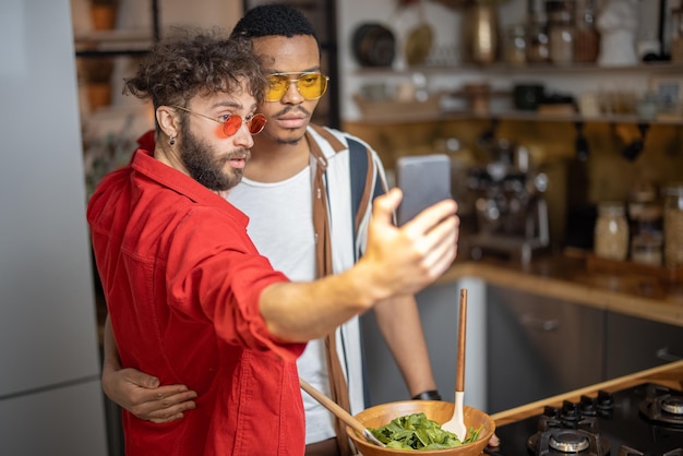 Two brightly dressed stylish guys taking selfie on phone indoors