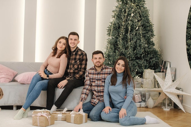 Two brother with their wifes at new year photosession beautiful woman and man in front of fir tree