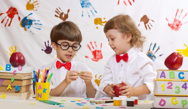 Due fratelli di 7 e 4 anni vestiti con magliette bianche con fiocchi rossi stanno giocando insieme.