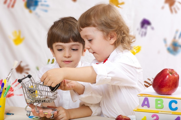 Due fratelli di 7 e 4 anni vestiti con magliette bianche con fiocchi rossi stanno giocando insieme.