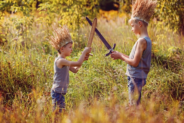 Two Brothers have a crown from dry grass on the head and swords in hands. 