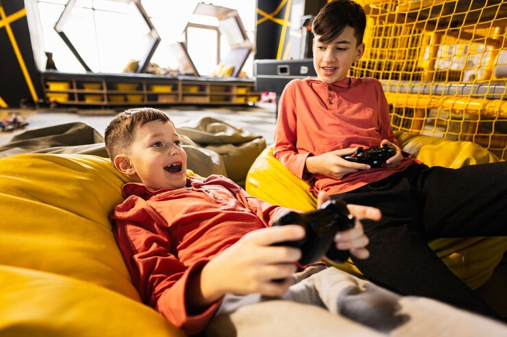 Photo 子供のプレイ センターで黄色のなよなよした男に座ってビデオ ゲーム コンソールを遊んでいる 2 人の兄弟