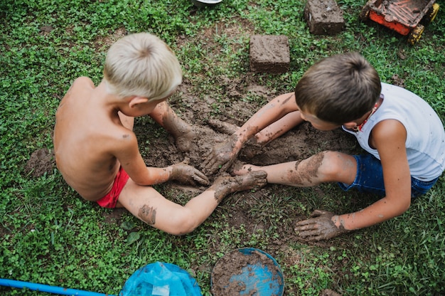 Two brothers playing with mud