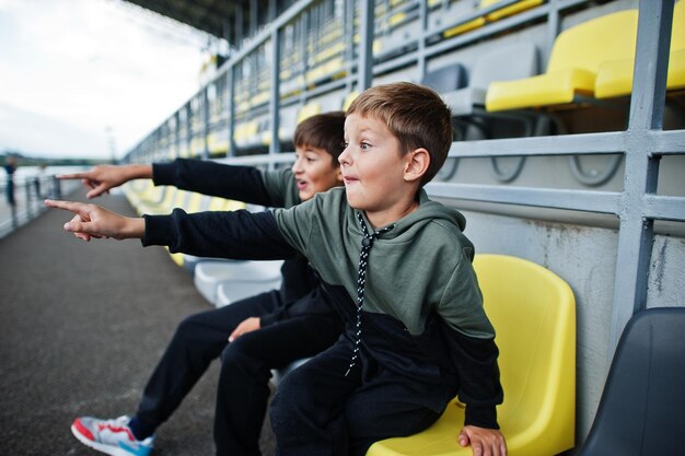 Two brothers support their favorite team sitting on the sports podium at the stadium