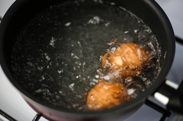 Two brown eggs in a pot of boiling water