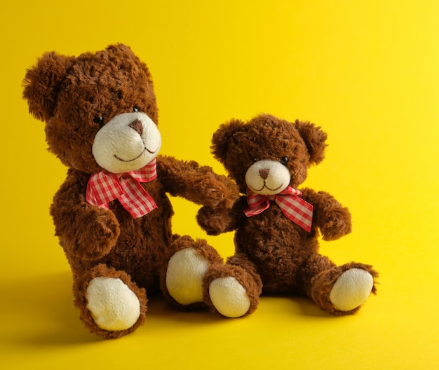 Two brown teddy bears on yellow 