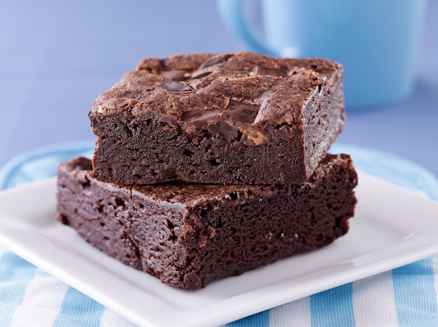 Two brownies stacked on a plate.