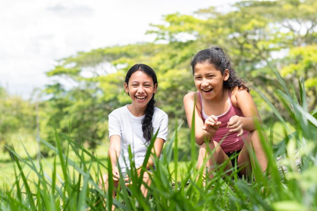 Foto due ragazze brune latine molto felici sorridendo e parlando sedute in un parco verde