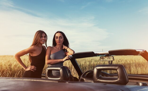 Two brunette women standing near her car