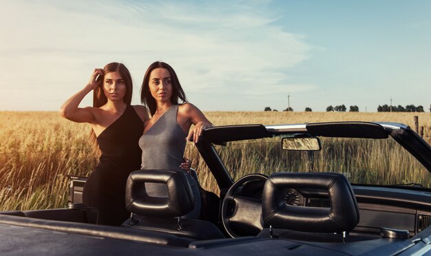 Two brunette women standing near her car