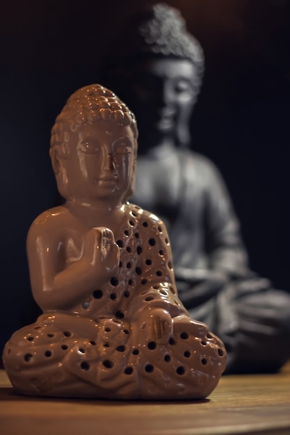 Two Buddha statuettes on a wooden table