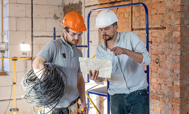 Two builder engineers talking at building site, engineer explaining a drawing to a worker