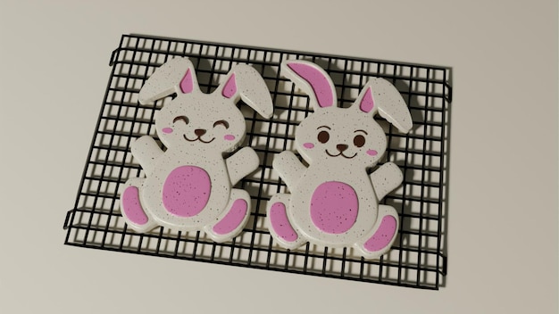 Photo two bunny cookies with pink and white bunnies on them sit on a cooling rack.