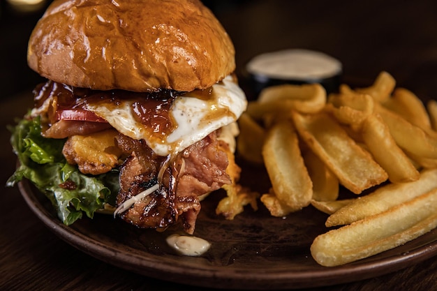 Two burgers and fries on wooden board big half pound patty with melted real cheddar and lot of sauce