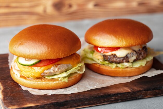 Two burgers on wooden board on gray table