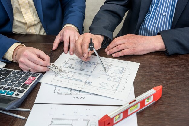 Two busimessman working with house architectural plan at office desk