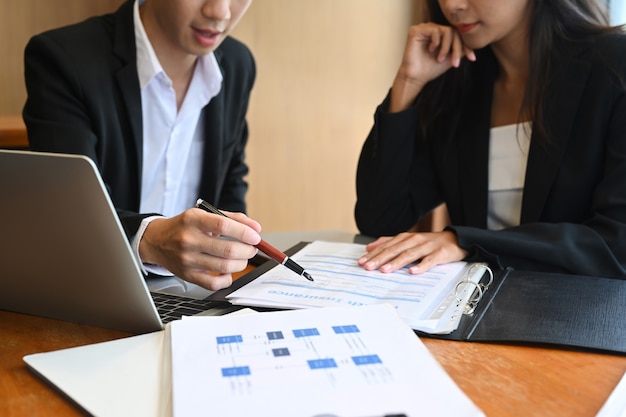 Two business colleagues analyzing financial reports in office.