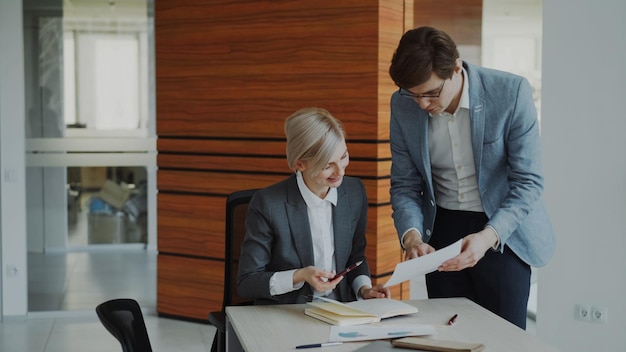 Two business colleagues discussing reports in modern office