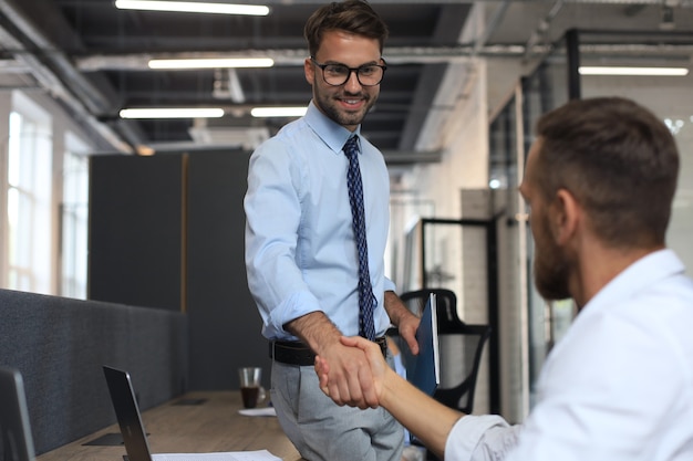 Due colleghi di lavoro si stringono la mano durante la riunione.