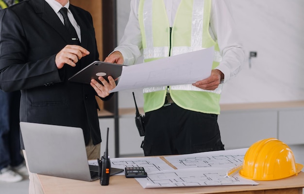 Two business man construction site engineer Engineering objects on workplace with partners interacting on background