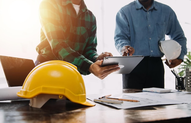 Two business man construction site engineer engineering objects on workplace with partners interacting on background