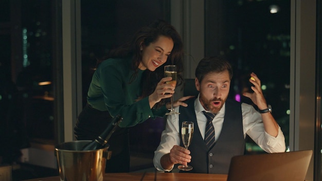 Two business partners exciting by success holding champagne in company office