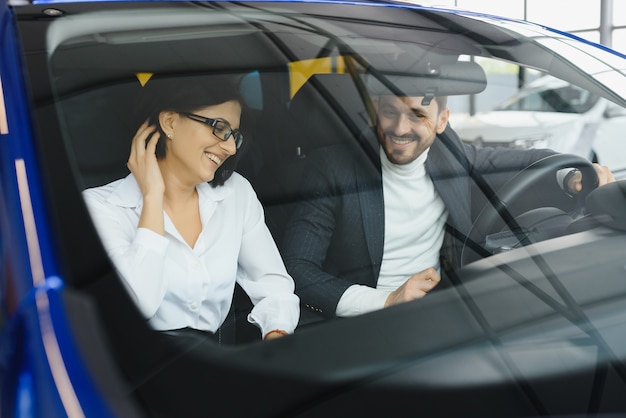 Two business people in classic wear analyzing documents while sitting in the car.