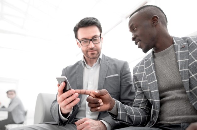 Two business people partners watching media content on a smartphone