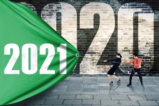 Two business people pulls banner with 2021 numbers